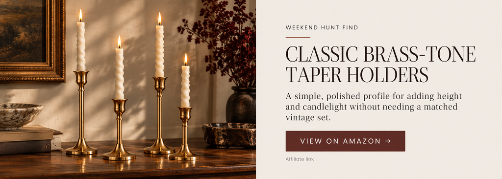 Classic brass-tone taper candle holders in varied heights styled with ivory candles on a warm wood surface.