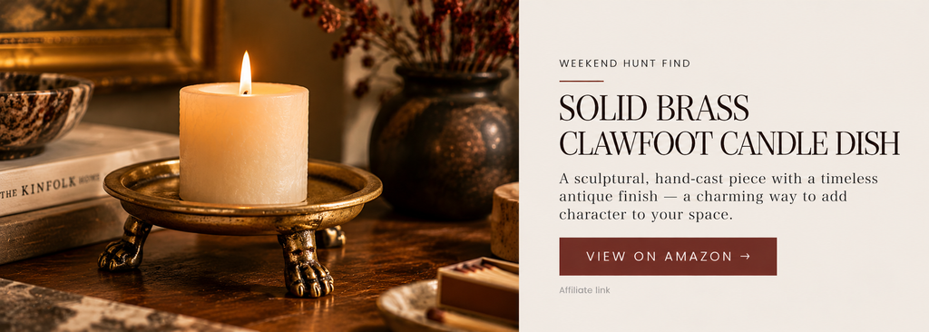 Low brass candle dish with a raised rim and sculptural claw feet holding an ivory candle.