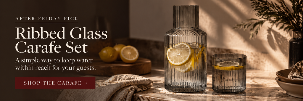 Smoke-grey ribbed glass carafe with matching tumbler styled on a warm dinner table for self-serve water.