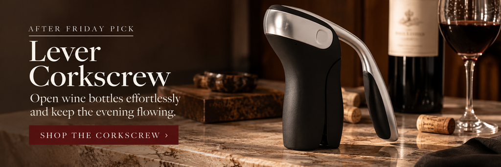 Black and silver lever corkscrew styled beside a bottle of red wine in a warm hosting setup.