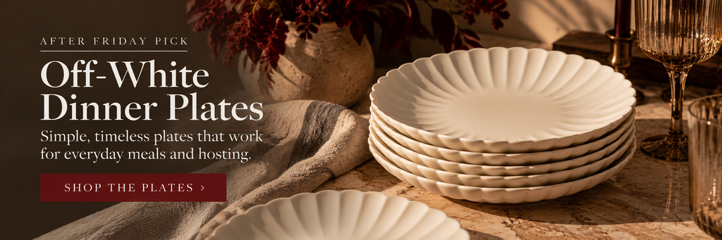 Scalloped off-white ceramic dinner plates styled on a simple candlelit dinner table.